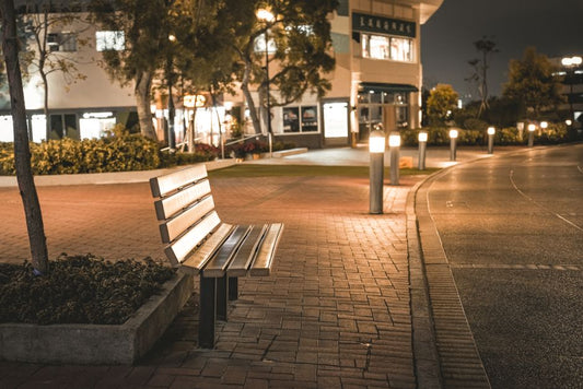 Black LED garden bollard light illuminating a pathway at dusk with shrubs and planting on either side
